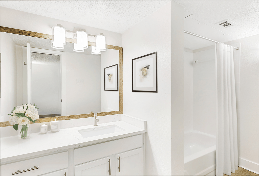 Virtually staged bathroom with white quartz countertop, white cabinetry, large mirror and white shower curtain